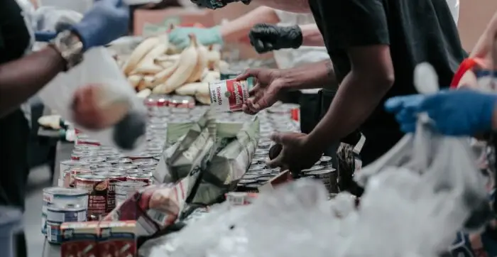 akcijski posnetek menjalnice banke hrane s konzerviranimi izdelki v ospredju in bananami v ozadju